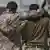 Dois soldados abraçados, vistos pelas costas