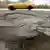 A close up photo of potholes on a German street with a yellow car driving by