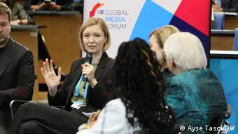 Ukrainian journalist Angelina Kariakina talks into the microphone and looks towards her fellow panelists Věra Jourová and Claudia Roth at the 2022 conference discussion on journalism in wartimes.