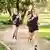 Three people running through a park, wearing black shorts and t-shirts.
