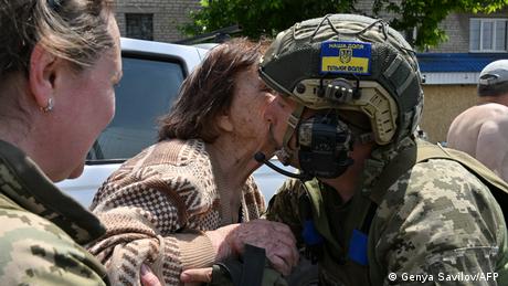 Eine ältere Frau küsst einen ukrainischen Soldaten, nachdem sie aus einem überfluteten Gebiet in Cherson evakuiert wurde.