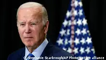 A stern looking Joe Biden in front of a US flag