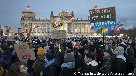 A massive crowd of people stand in front of the Reichstag in Germany's capital Berlin holding placards.