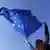 Mujer hace ondear al viento una bandera de la UE.
