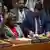 Linda Thomas-Greenfield sitzt mit erhobener rechter Hand am runden Tisch des UN-Sicherheitsrates, umgeben von anderen Diplomaten