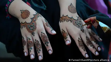 A woman shows her hands covered in henna designs