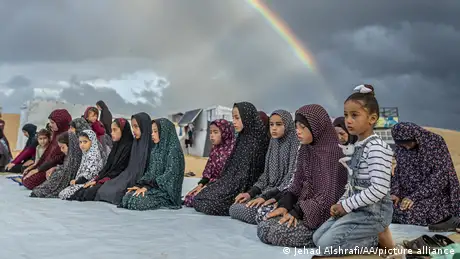 Children are seen praying outdoors